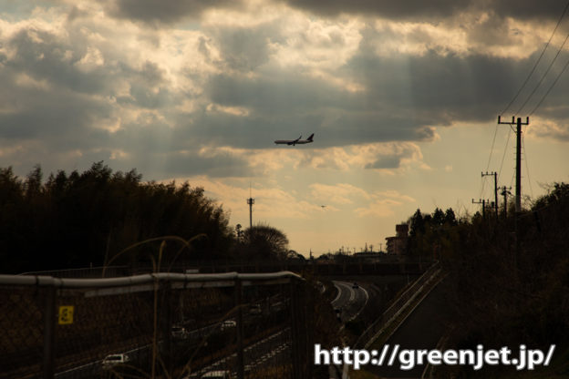 高速道路の向こうを行く飛行機に光芒～渋！